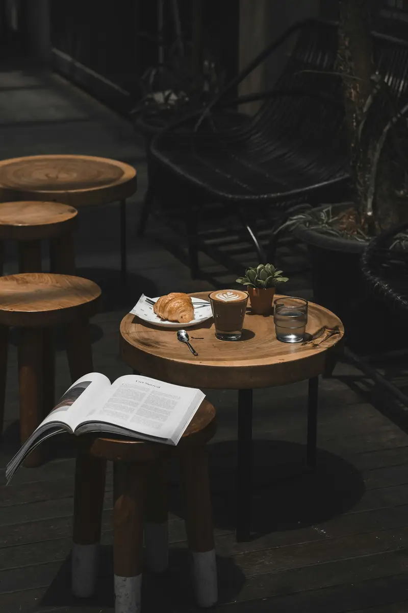 A latte, croissant and book on a café table